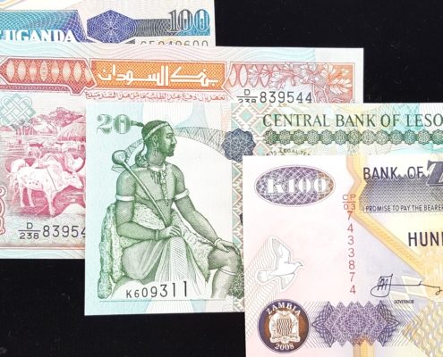 Overlapping banknotes of Uganda, Sudan, Lesotho, and Zambia